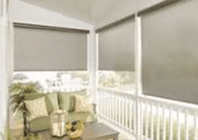 A porch with two windows covered in roller shades.