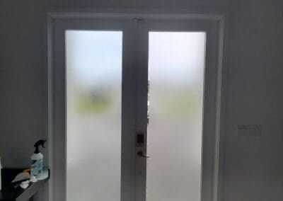 Frosted glass double doors in a room with light-colored floors.