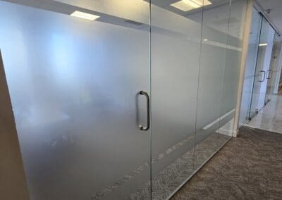 Frosted glass door with a metal handle in an office corridor.